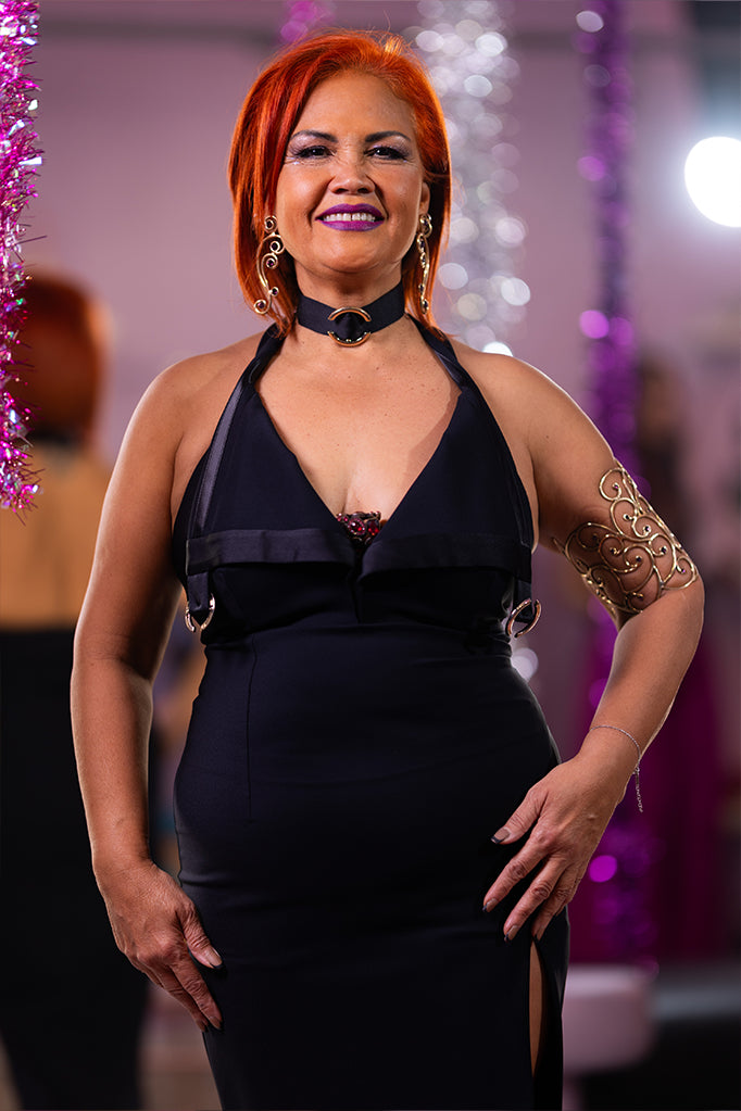 Modella posa sorridente con abito nero Babylon e spacco accentuato