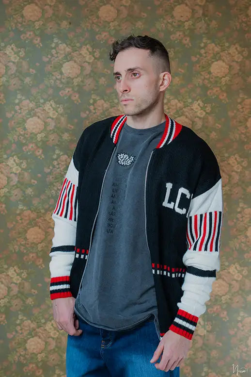 Modello indossa cardigan fullzip LES COSTUMES in acrilico nero con logo jacquard, vista frontale completa