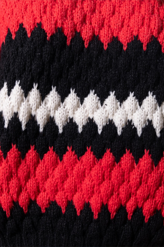 Dettaglio texture intrecciata del maglione rosso e nero con filato spesso a zigzag
