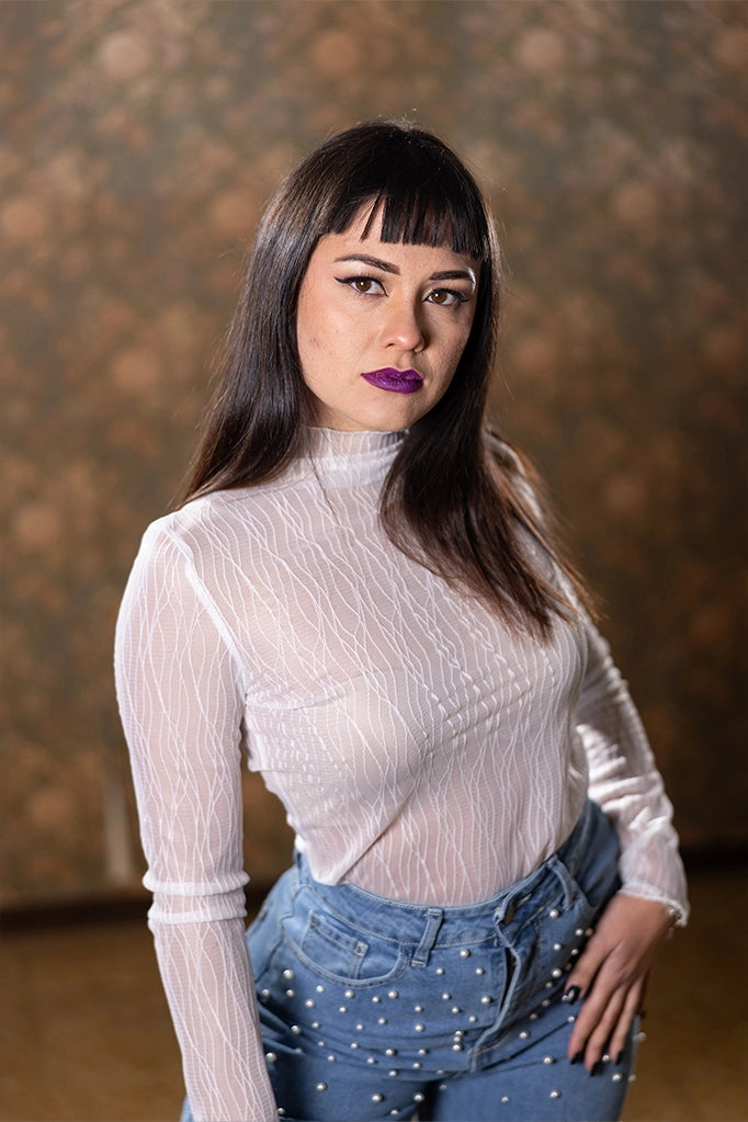 Modella con maglia lupetto bianco semi-trasparente in tulle, vista laterale elegante