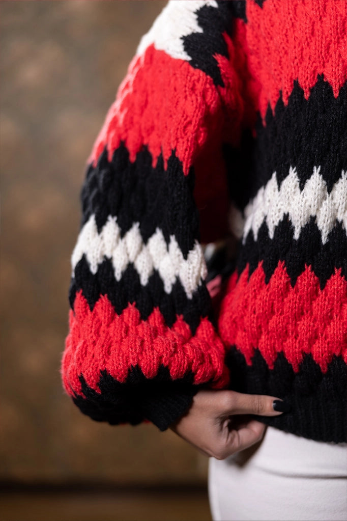 Primo piano su manica maglione zigzag Anna Rock in rosso, nero e bianco, lavorazione spessa