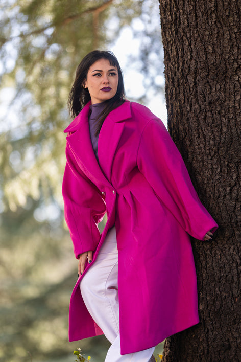 Donna con cappotto lungo fucsia Monique Garçonne e make-up intenso, posa glamour