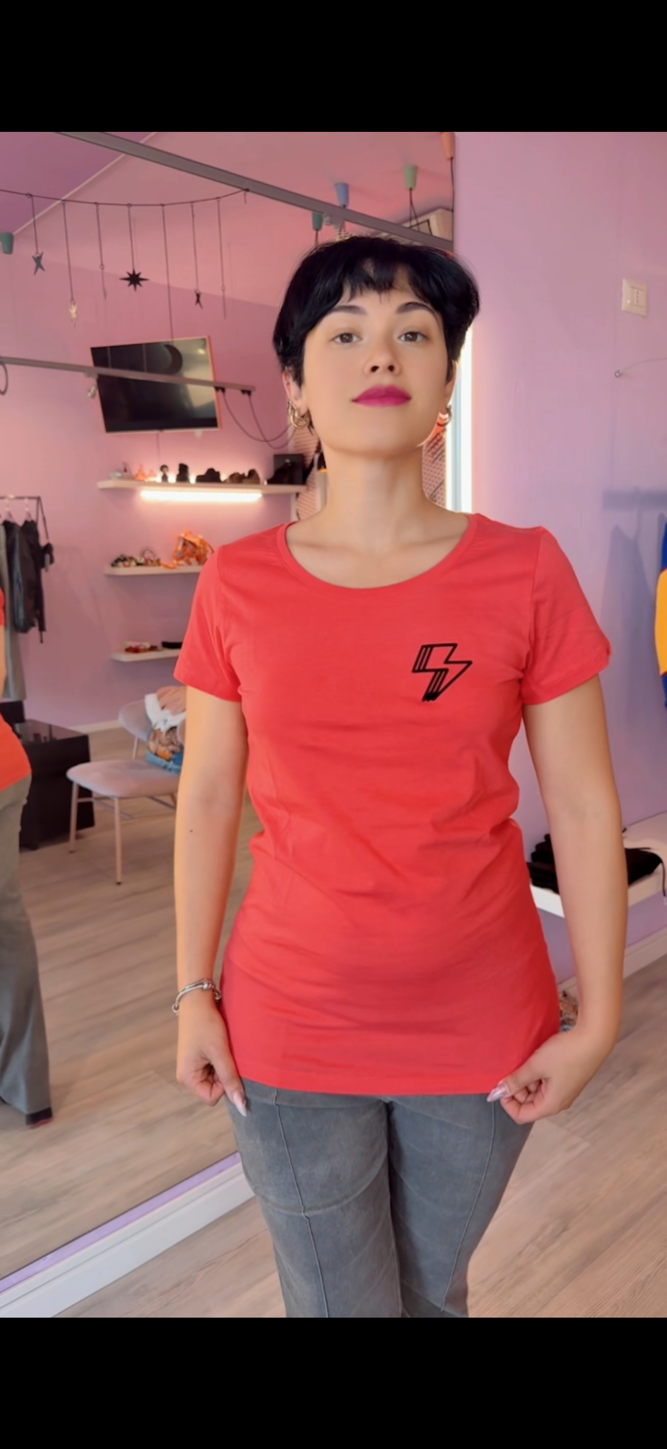 T-shirt a maniche corte color corallo in cotone leggero estivo firmata KK Shop, con stampa frontale a forma di fulmine nero con texture flok effetto velluto, posizionata su sfondo neutro da e-commerce