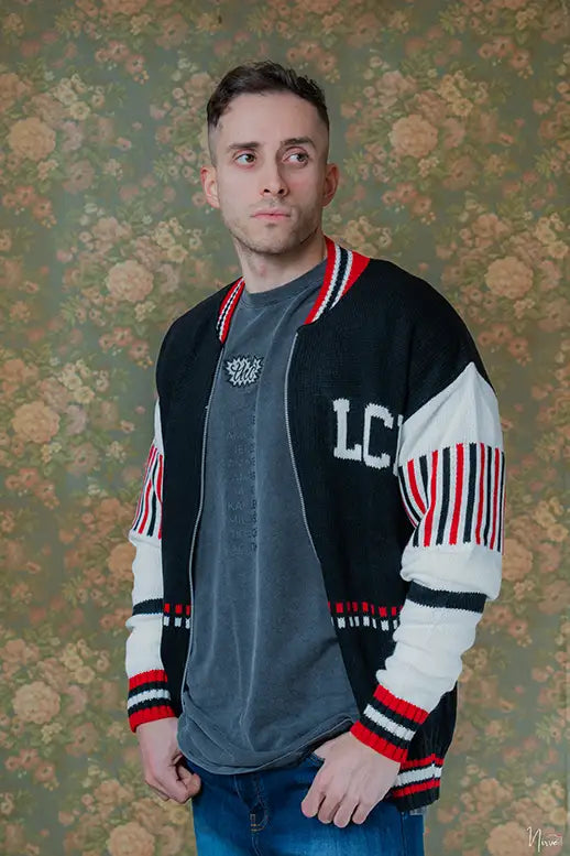 Modello indossa cardigan fullzip LES COSTUMES in acrilico nero con logo jacquard, vista frontale 3/4