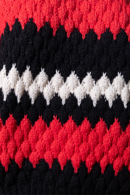 Dettaglio texture intrecciata del maglione rosso e nero con filato spesso a zigzag
