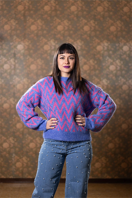 Maglione fantasia zig zag rosa e lilla Anna Rock, indossato da modella con jeans borchiati
