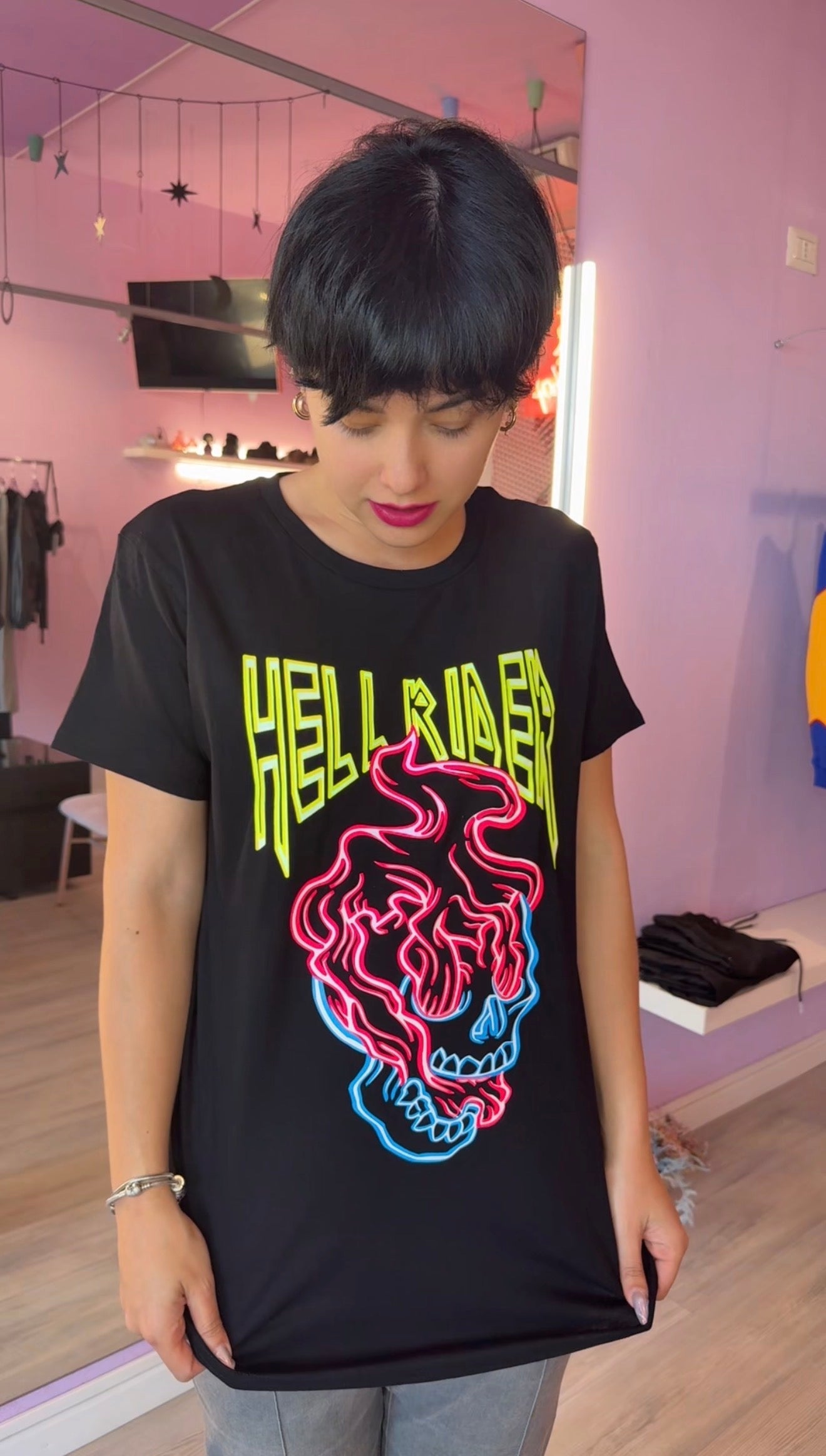 T-shirt unisex a maniche corte color nero con stampa frontale di un teschio luminoso in stile neon e scritta Hell Rider, fotografata su sfondo neutro per e-commerce.